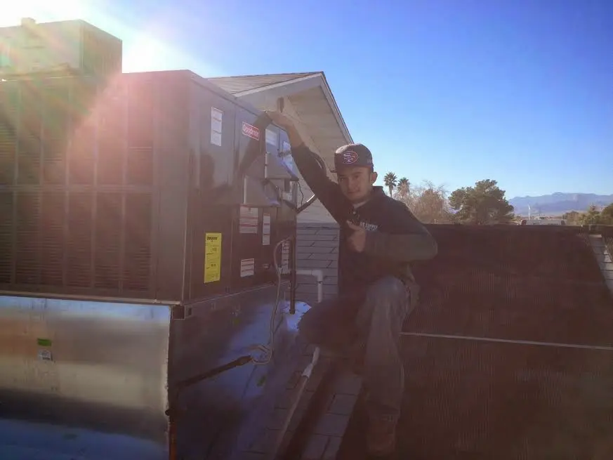 HVAC technician performing Heat Pump Repair on a rooftop unit in Leighton